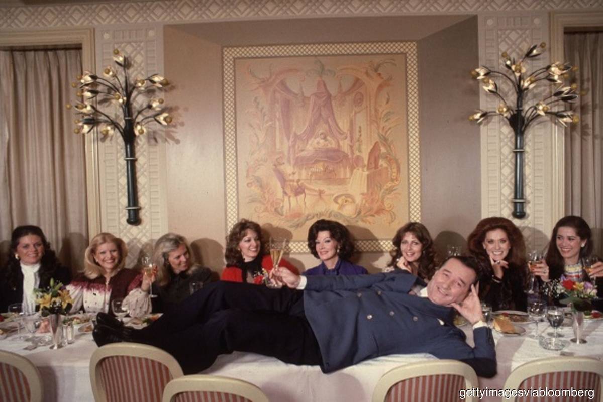 The late Sirio Maccioni hams it up in a 1981 photo with ladies who lunched. (From left: Kathryn Penske, Ivana Trump, Muffie Bancroft, Anne Arledge, Anna Moffo Sarnoff, Cristina DeLorean, Maria Kimberly, and Patricia Kluge.) (Photo credit: Slim Aarons/Getty Images via Bloomberg)