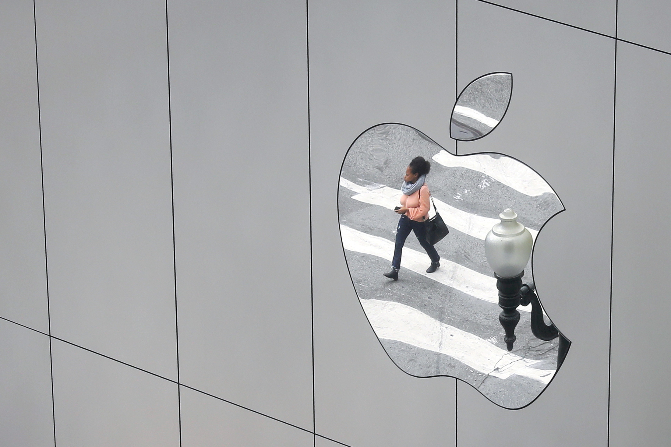 A woman is reflected in a Apple store logo in San Francisco, California, U.S., August 21, 2017.