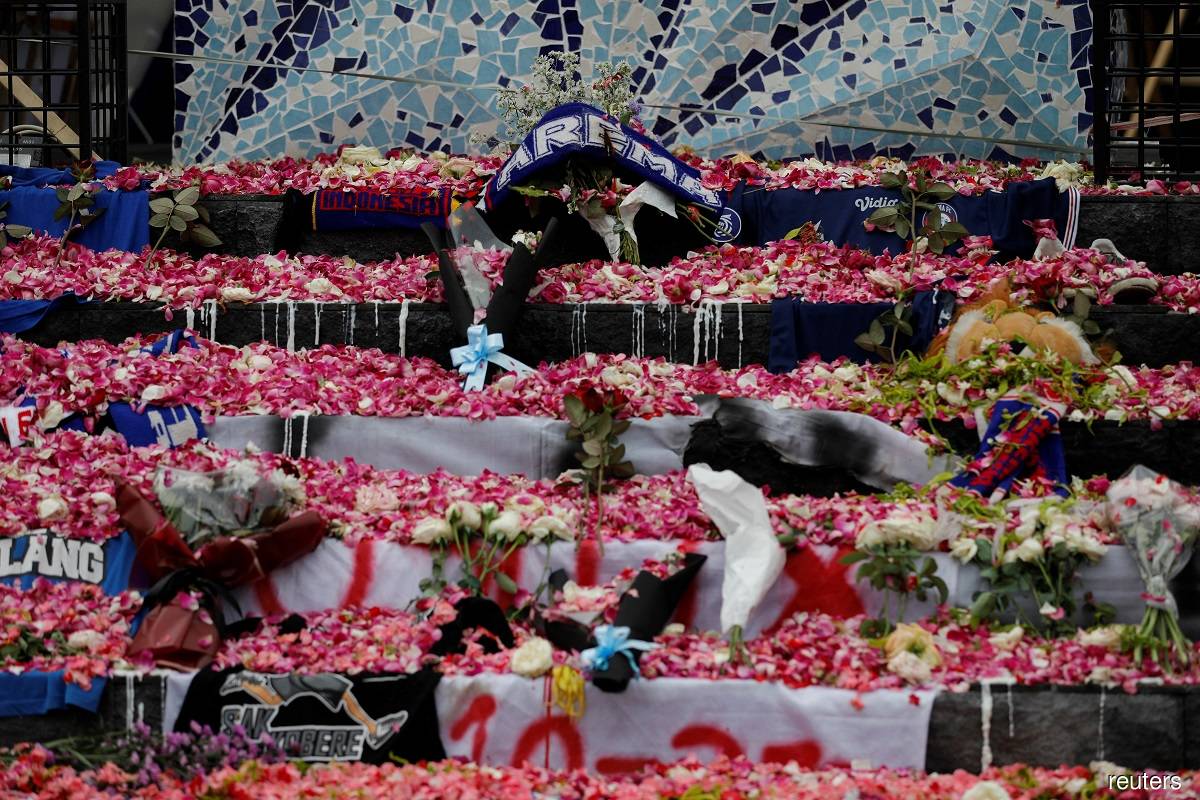 Petals and Arema FC supporters' attributes are placed on a monument to pay condolence to the victims of a riot and stampede following a soccer match between Arema FC and Persebaya Surabaya teams, outside the Kanjuruhan Stadium, in Malang, East Java province, Indonesia, Oct 3, 2022.