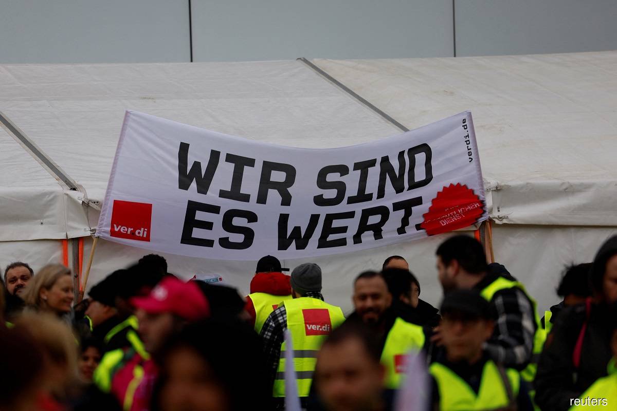 Workers hold a banner which reads 'We are worth it' during a strike, after German trade union Verdi called on workers at Frankfurt, Munich, Stuttgart, Hamburg, Dortmund, Hanover and Bremen airports to go on a 24-hour strike, in Frankfurt, Germany Feb 17, 2023.