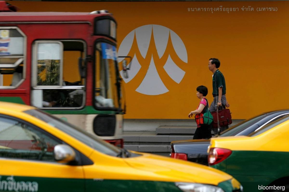 The logo of Bank of Ayudhya is seen on a wall outside a building in Thailand, as traffic and pedestrians pass by. (Bloomberg pix)