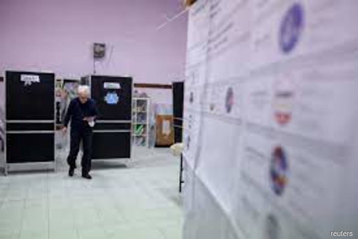 A man holds ballots in his hand as he walks inside a polling station during the snap election in Rome, Italy on Sunday, Sept 25, 2022. (Photo by Stoyan Nenov/Reuters)