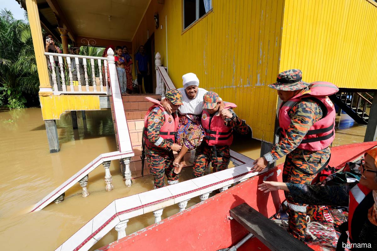 Fire and Rescue Department personnel lifting 79-year-old Dodie Dray into a boat to be evacuated after her home at Kampung Rancangan Cocos, Pamol, Sabah was flooded on Jan 26, 2023.
