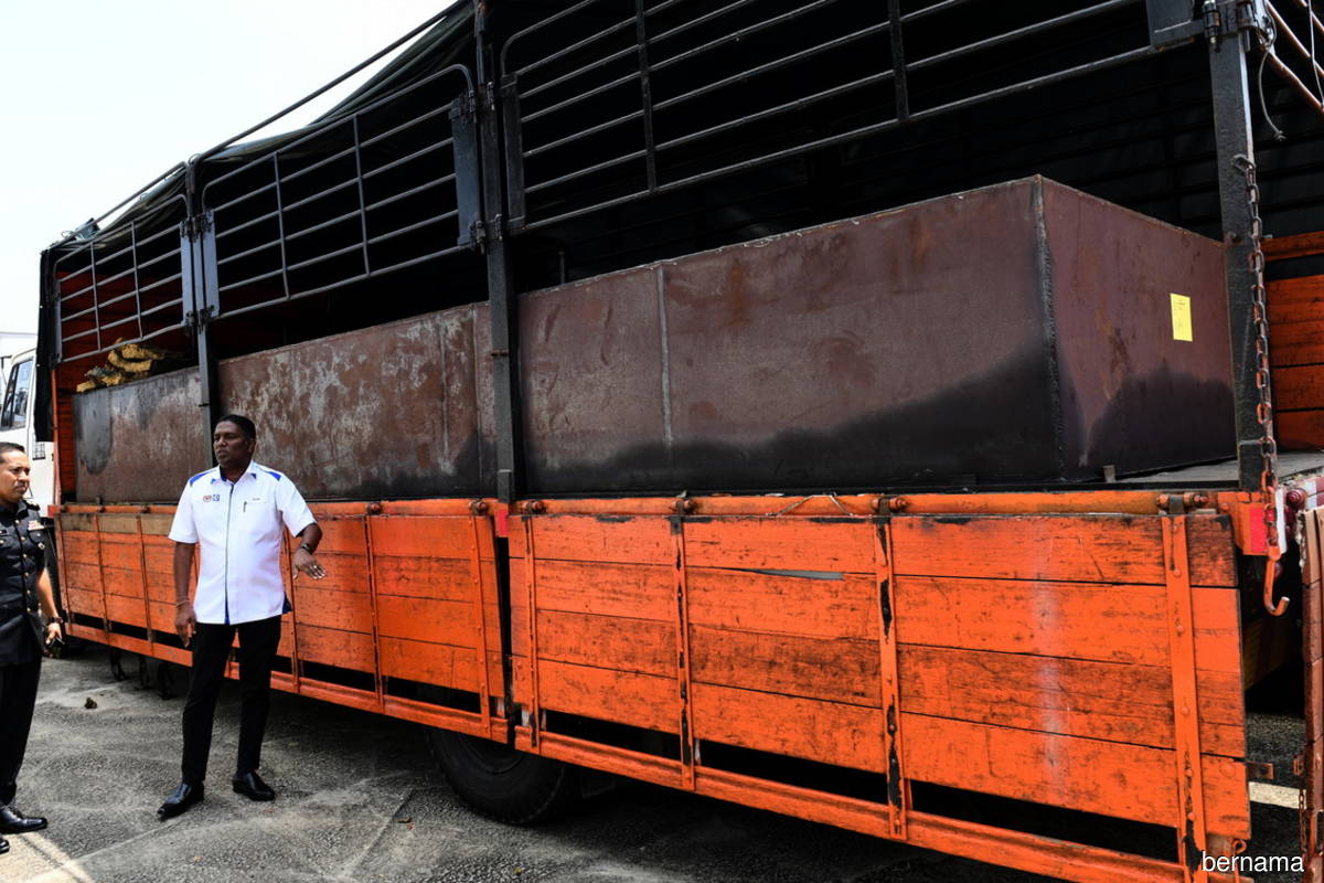 Penang Ministry of Domestic Trade and Cost of Living director S Jegan (right) with the seized lorry that had been modified to carry out subsidised diesel embezzlement activities