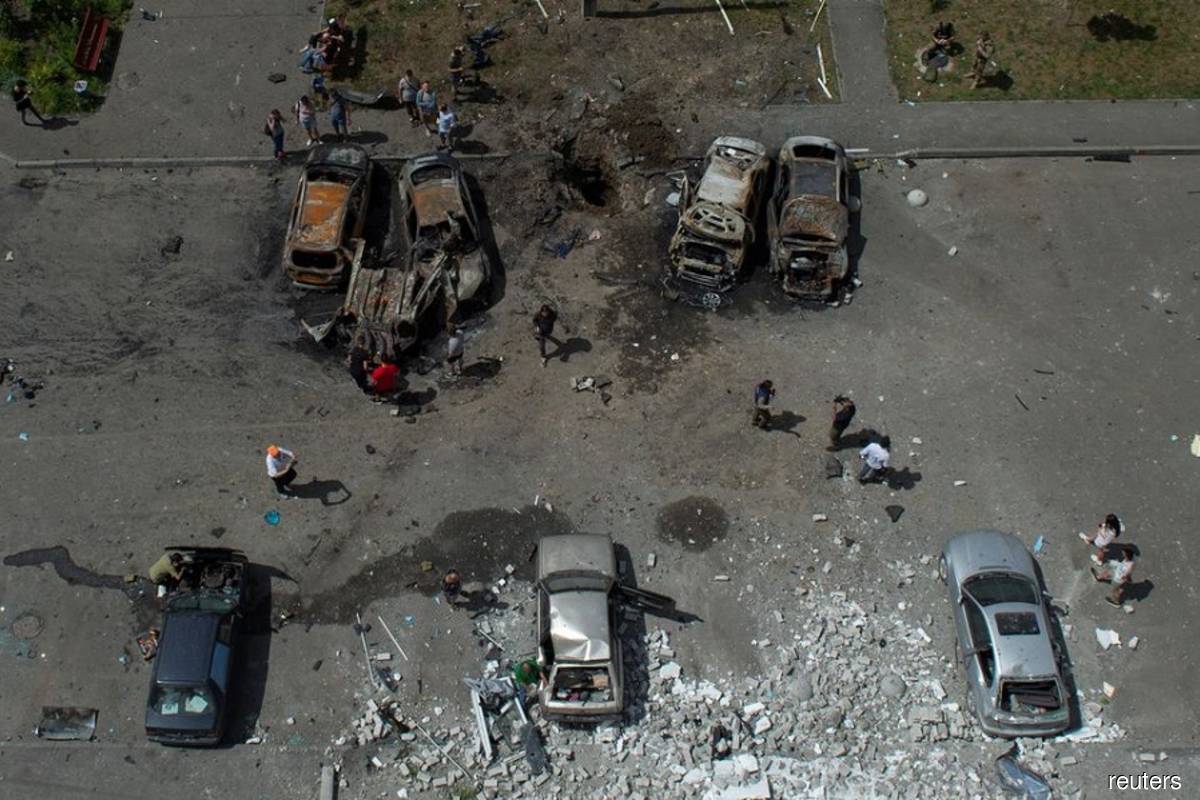 People stand next to cars destroyed by a Russian missile strike, as Russia's attack on Ukraine continues, at a residential area in Kharkiv, Ukraine on June 26, 2022. (Reuters filepix by Sofiia Gatilova)