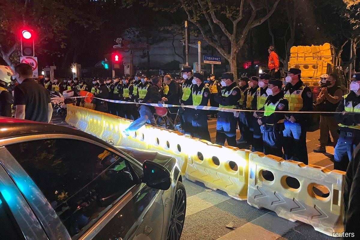 Police officers stand behind barricades and cordon at the site in Shanghai, China on Nov 27, 2022, where a protest against Covid-19 curbs took place the night before, following the deadly Urumqi fire. (Reuters filepix by Josh Horwitz)