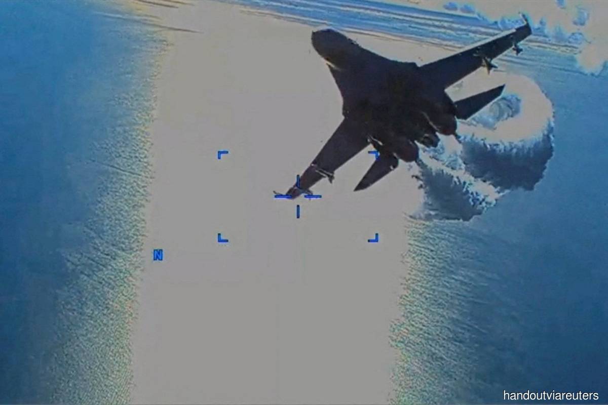 A Russian Su-27 military aircraft dumps fuel while flying by a US Air Force MQ-9 "Reaper" drone over the Black Sea on March 14, 2023 in this still image taken from a handout video released by the Pentagon. (Photo credit: US European Command/The Pentagon/Handout via Reuters)