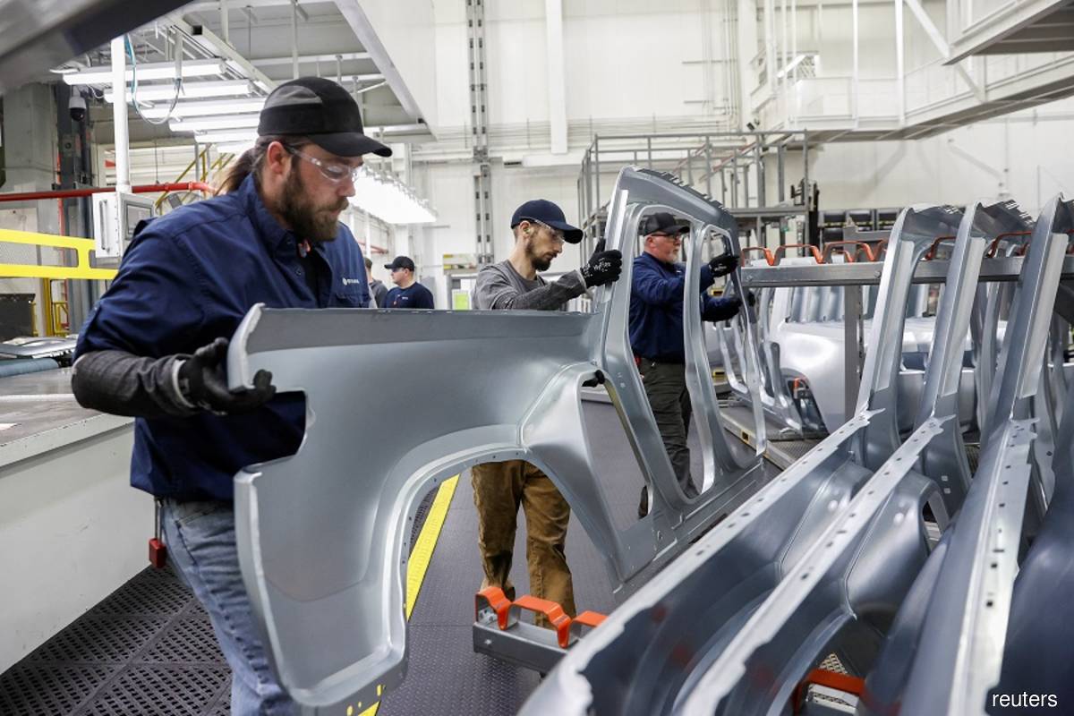 Employees work on an assembly line at startup Rivian Automotive's electric vehicle factory in Normal, Illinois, US on April 11, 2022. (Reuters filepix by Kamil Krzaczynski)