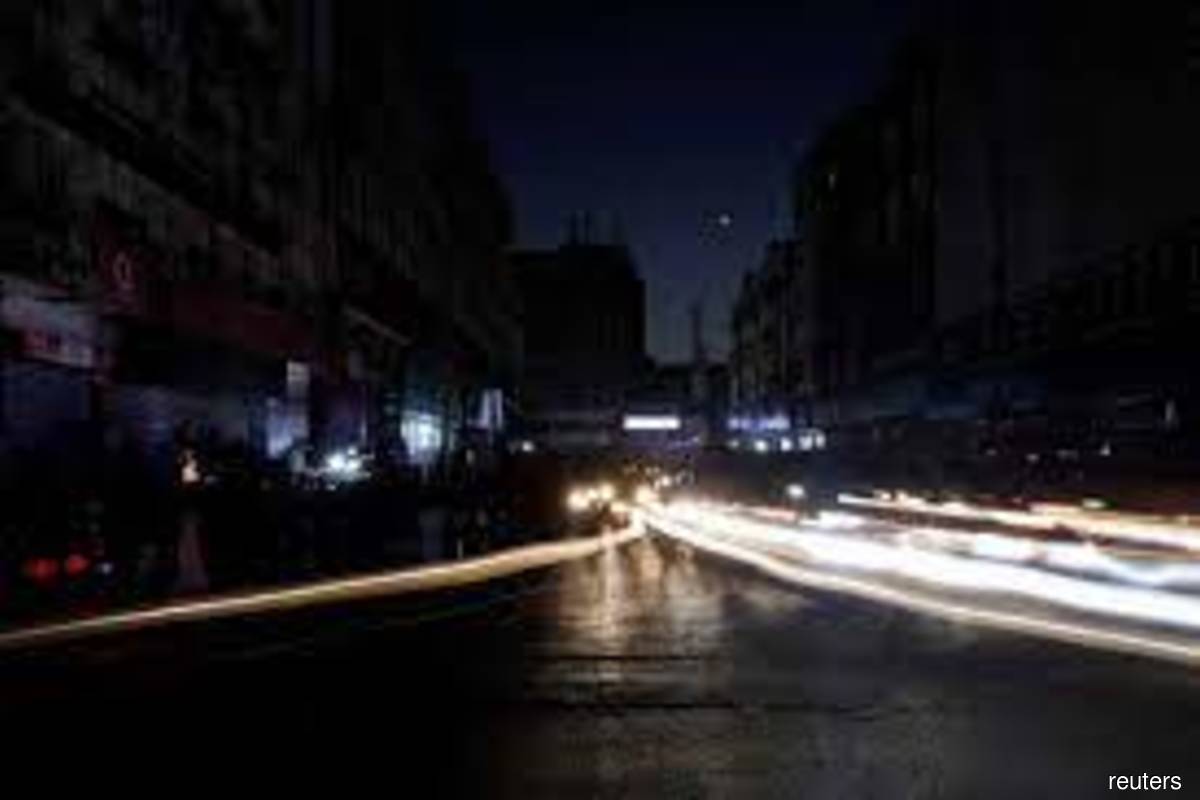 Vehicle lights cause light streaks on the road along a market, during country-wide power breakdown in Karachi, Pakistan on Jan 23, 2023. (Reuters filepix by Akhtar Soomro)