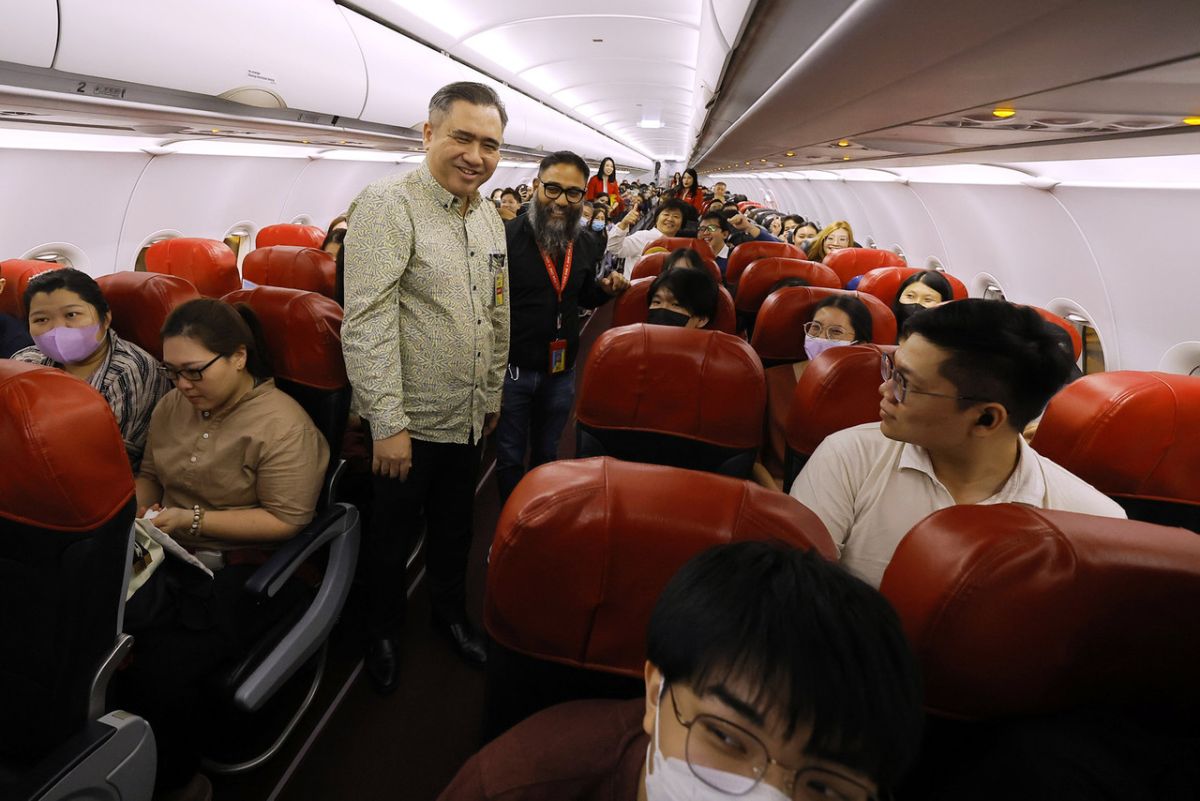 Transport Minister Anthony Loke chatting with AirAsia passengers on board a special additional flight offered in conjunction with Chinese New Year celebrations at klia2 on Thursday night.