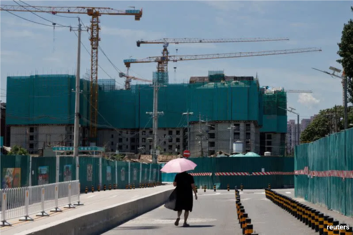 A woman walking near a construction site of apartment buildings in Beijing.