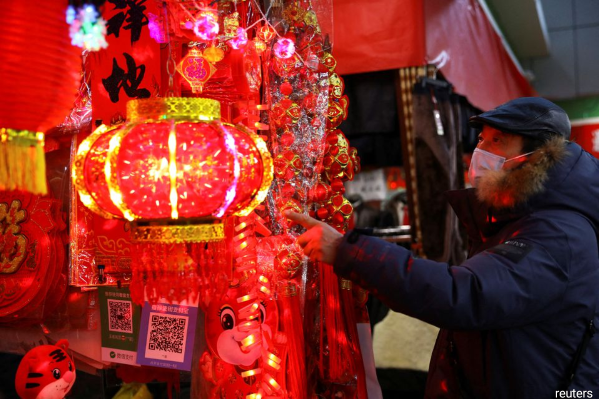 A customer looks at decorations for Chinese Lunar New Year displayed at a stall inside a morning market in Beijing, China on Jan 14, 2022.