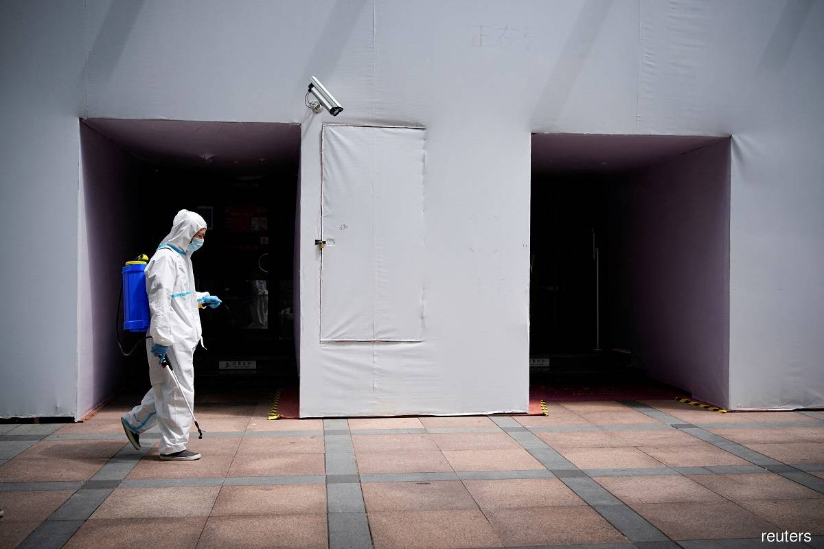 A worker in a protective suit disinfects following the Covid-19 outbreak, under a surveillance camera on street in Shanghai, China July 1, 2022.