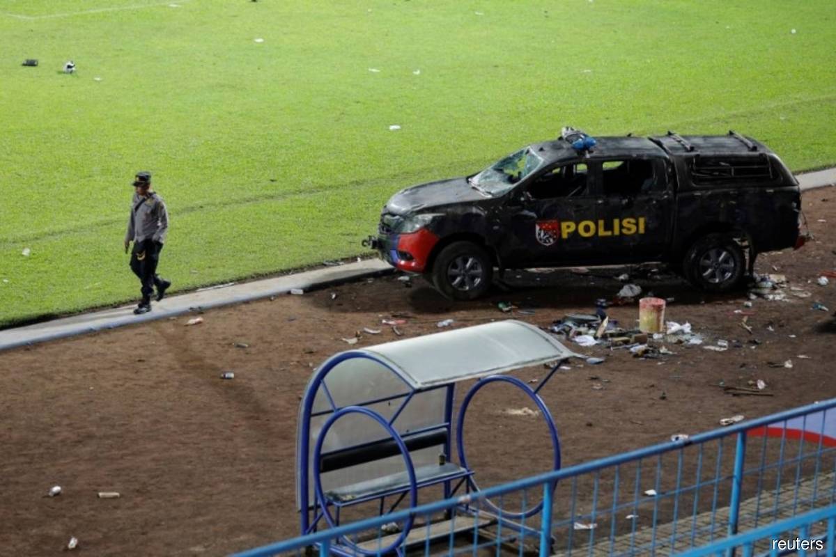 An officer walks as a damaged police vehicle is seen inside the Kanjuruhan Stadium on Sunday, October 2, 2022, where a riot and stampede took place following a football match between Arema and Persebaya, in Malang, Indonesia, the day before. (Reuters filepix)