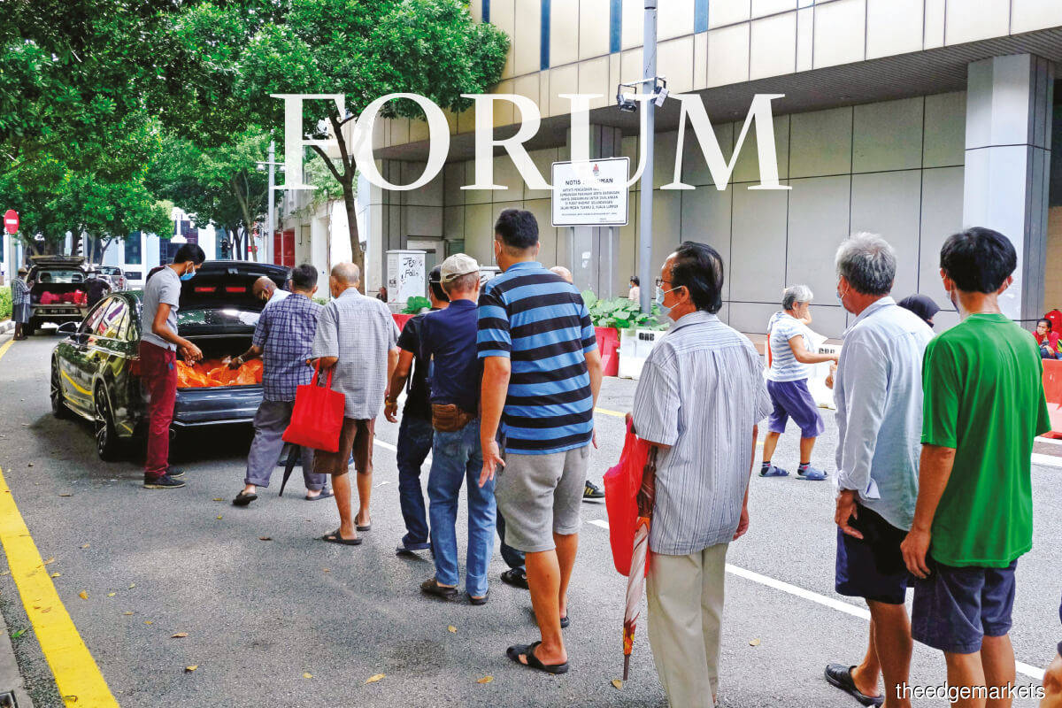 People stand in line to receive food donations near Central Market in Kuala Lumpur. The pandemic showed the resiliency and resourcefulness of Malaysians, over 90% of whom were born after Merdeka. (Photo by Bloomberg)