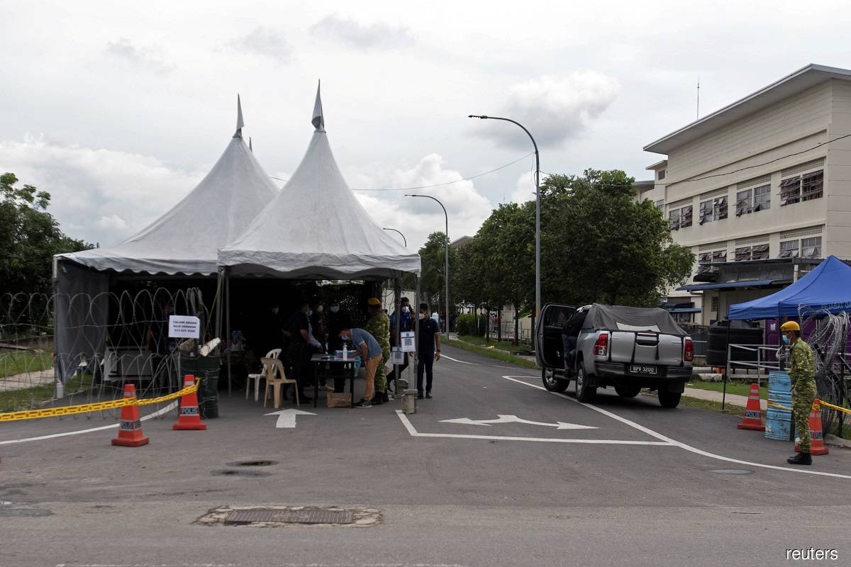 Law enforcement personnel seen guarding the entrance of Top Glove Corp Bhd's worker dormitories in Meru, Klang, Selangor today.