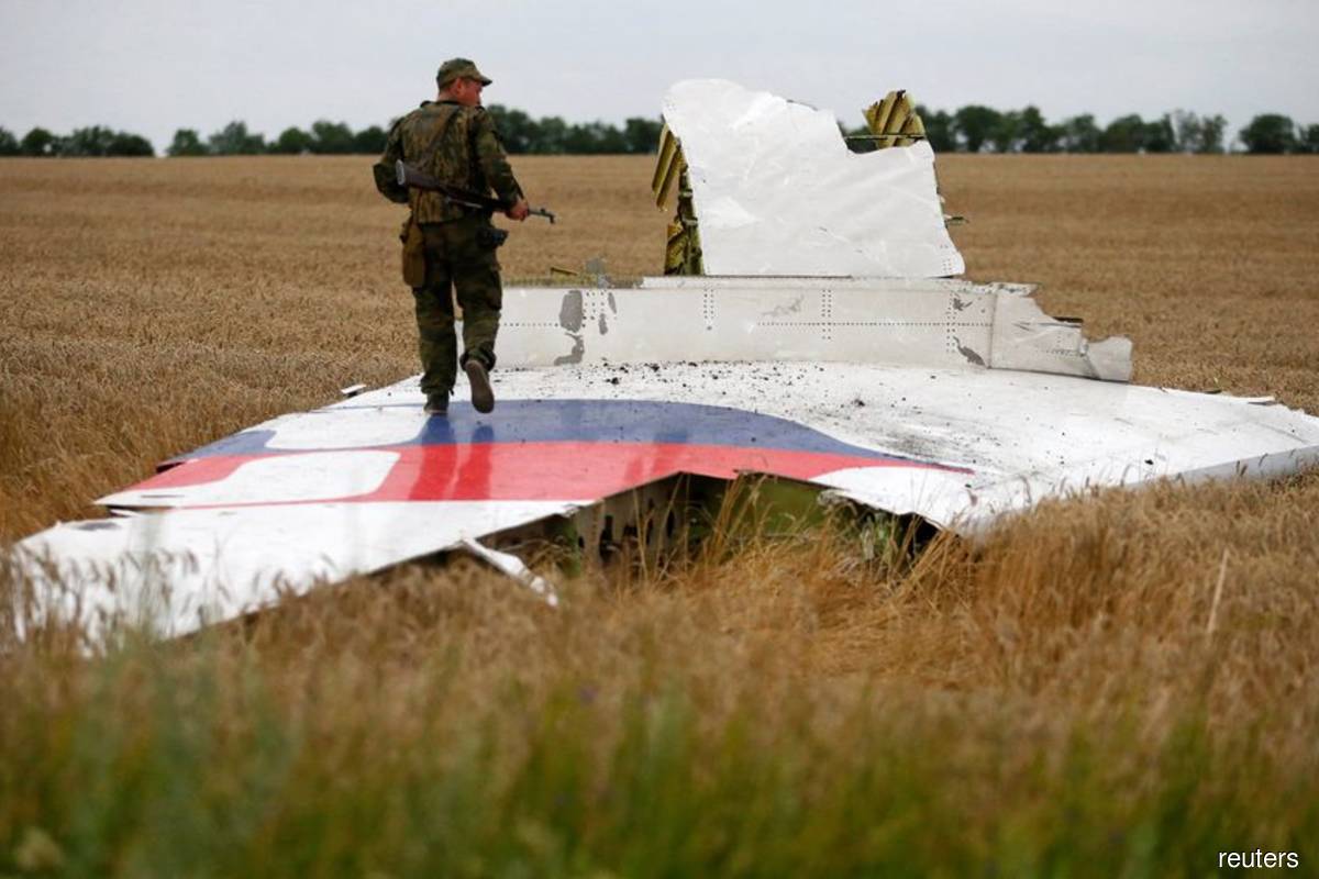 An armed pro-Russian separatist stands on part of the wreckage of the Malaysia Airlines Boeing 777 plane after it crashed near the settlement of Grabovo in the Donetsk region, July 17, 2014.
