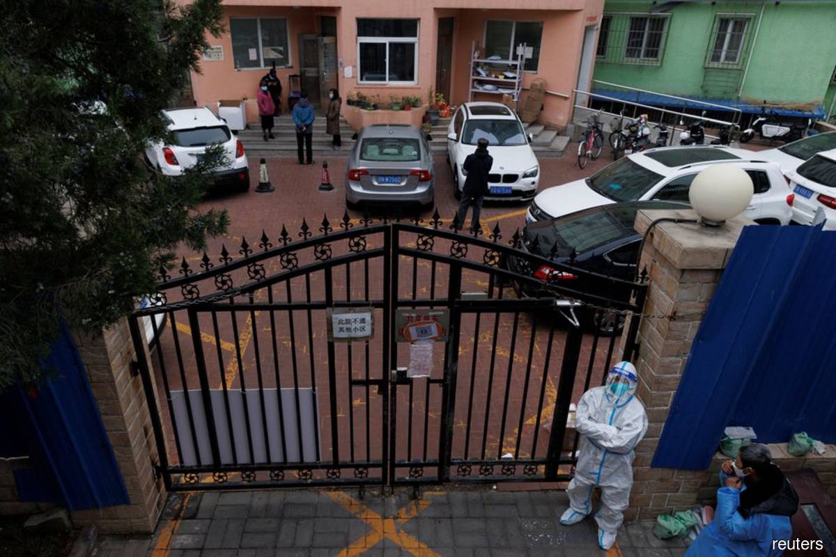 A pandemic prevention worker in a protective suit keeps watch at at a residential compound on Nov 18, 2022 after it was locked down, as outbreaks of the coronavirus disease (Covid-19) continue in Beijing, China. (Reuters filepix by Thomas Peter)