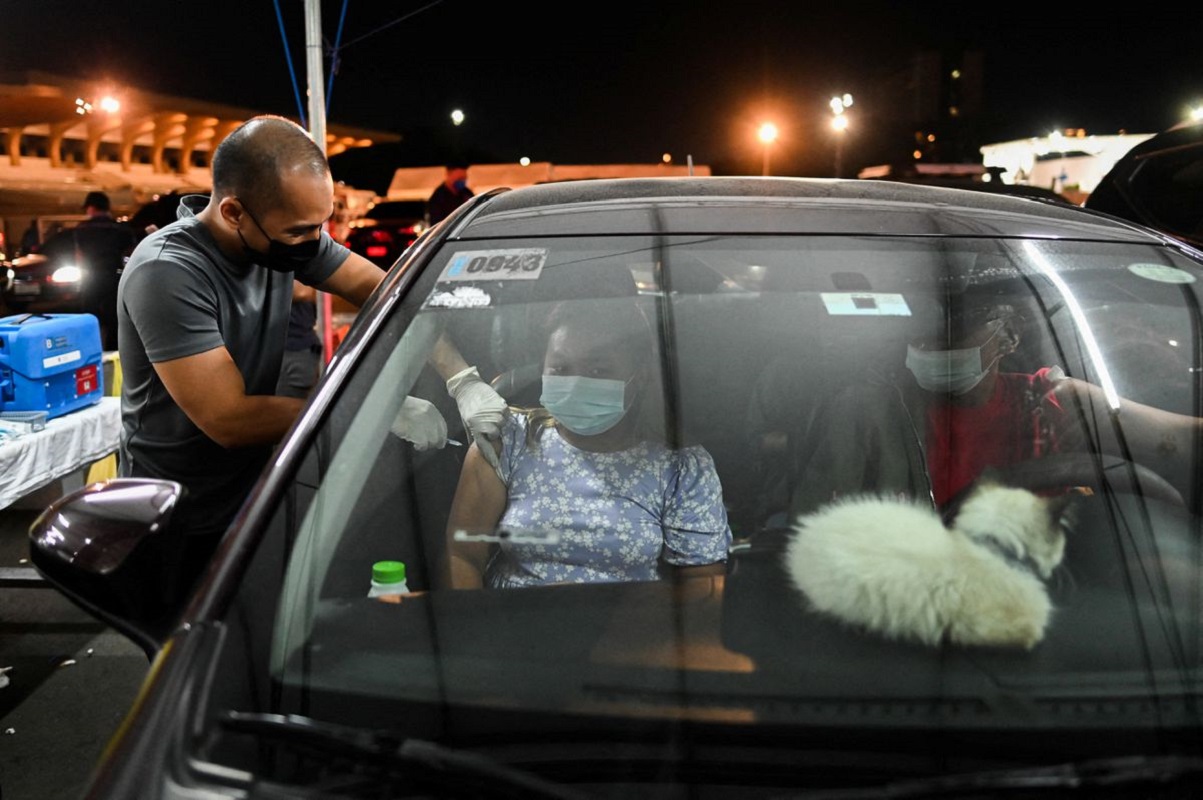 A woman receives a booster shot of the Pfizer Covid-19 vaccine, at a drive-through vaccination site, in Manila, Philippines, Jan 14, 2022. (Photo by Reuters)