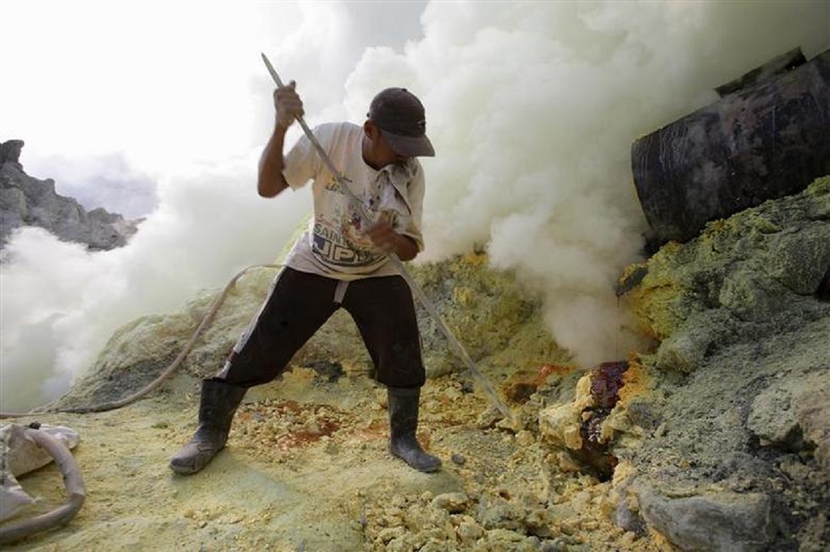 A miner bites on a wet towel to help him breathe through his mouth in the sulphurous fumes as he collects cooled sulphur at Kawah Ijen, a volcanic crater in Indonesia's East Java province, May 26, 2010. (File photo by Reuters)