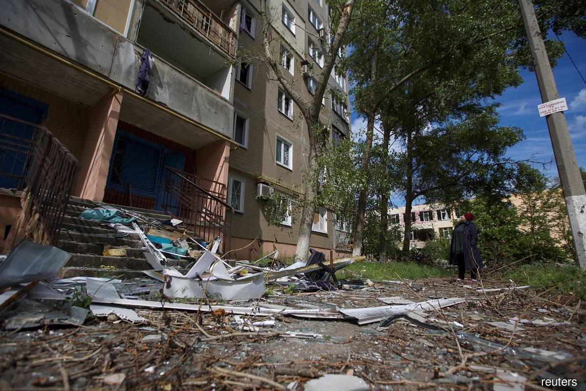 A local woman looks at an apartment building damaged by a Russian military strike, as Russia's attack on Ukraine continues, in the town of Vuhledar, in Donetsk region, Ukraine May 22, 2022. Picture taken May 22, 2022.