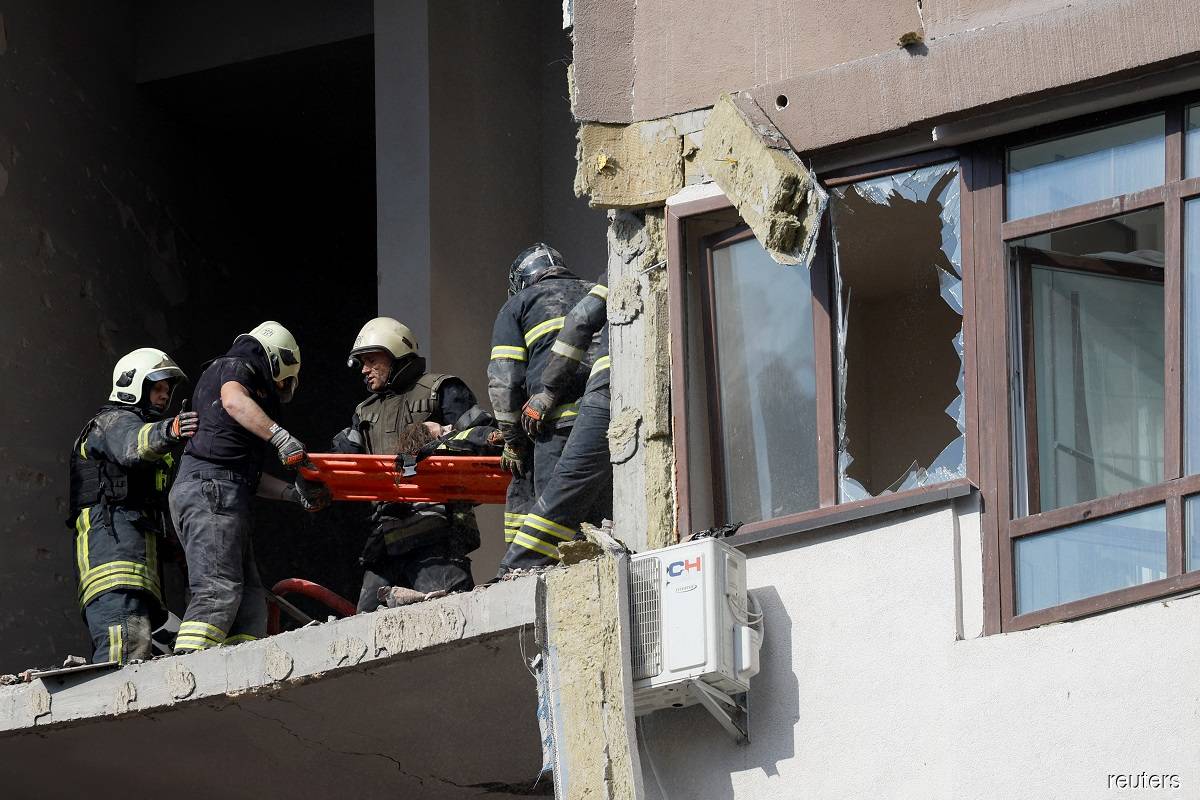 Rescue workers evacuating a person from a residential building damaged by a Russian missile strike in Kyiv, Ukraine on June 26, 2022.